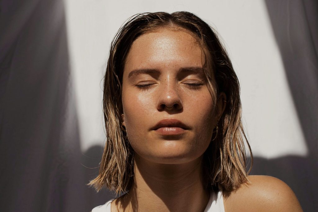 Woman with glowing skin taking a pic with her eyes closed